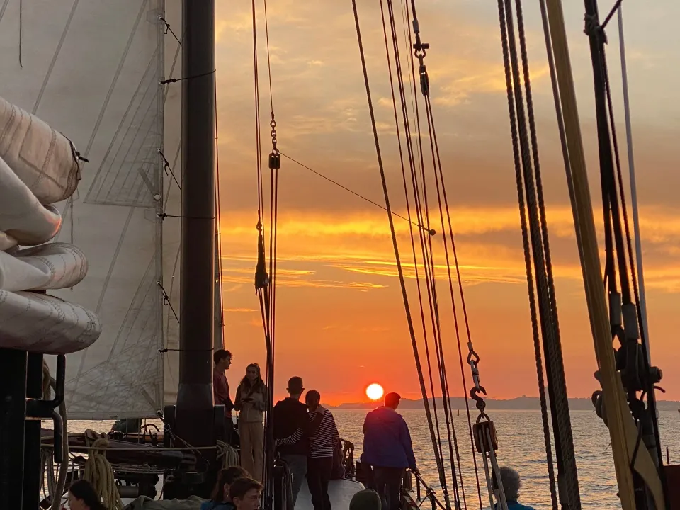 Gäste schauen vom Deck auf den Sonnenuntergang